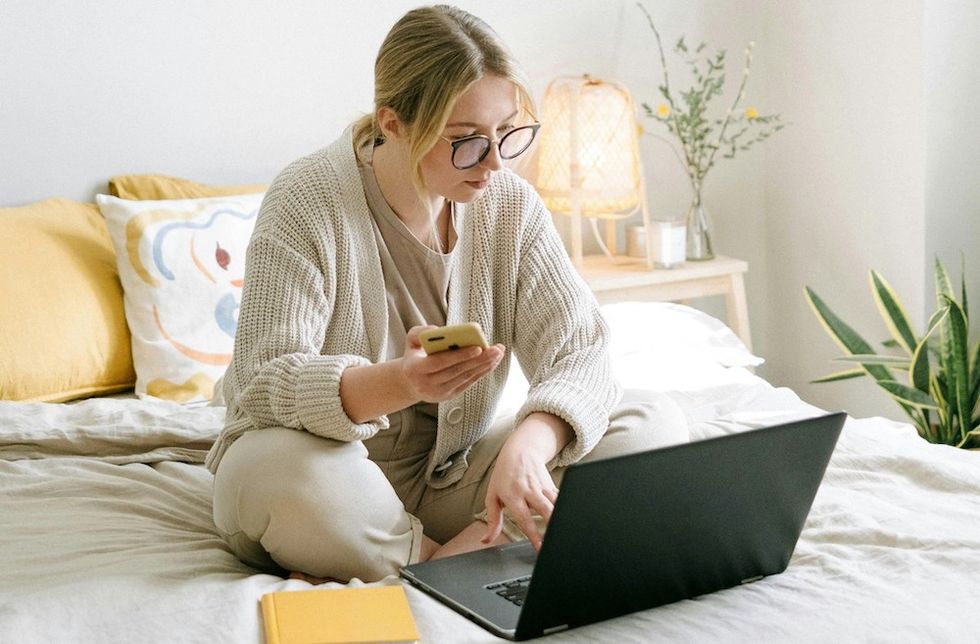 a woman texting while working on her laptop