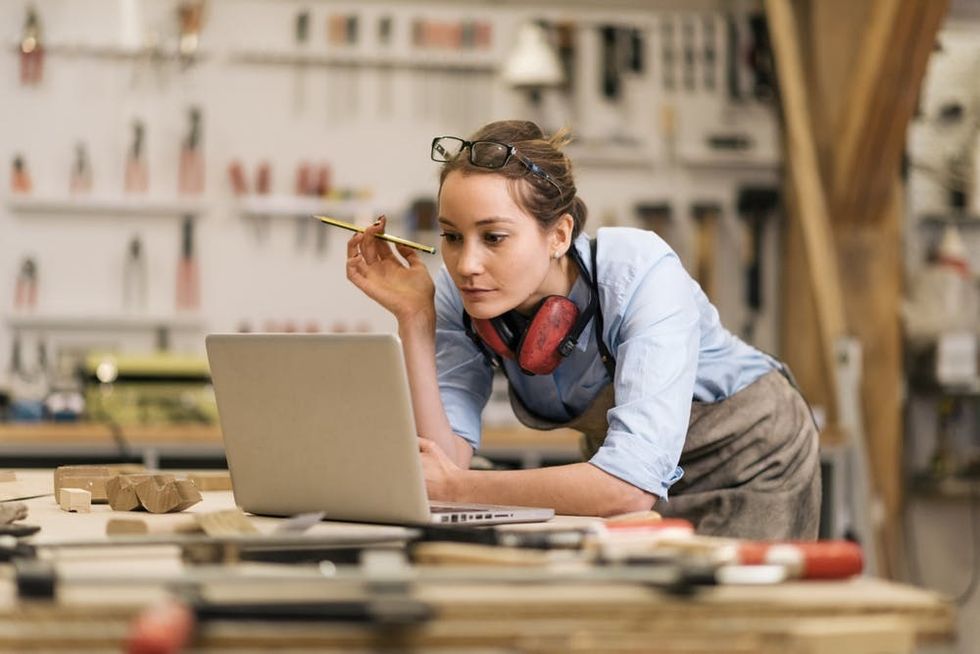 A woman uses a laptop in a carpentry workshop