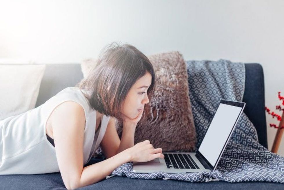 A woman uses a laptop on her sofa