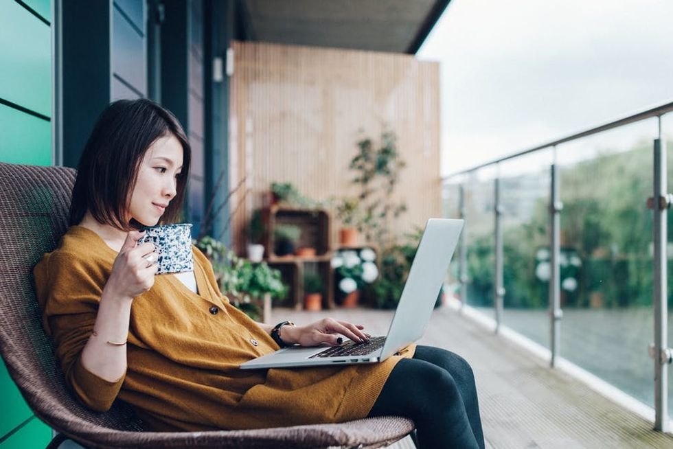A woman uses her laptop on her balcony