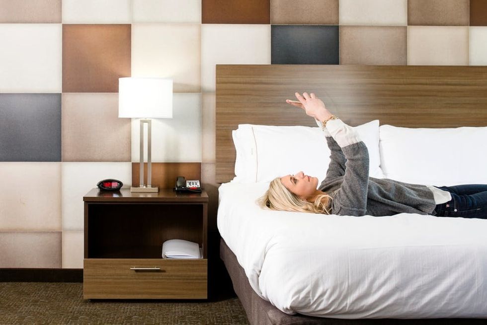 A woman uses her phone while lying on a hotel bed