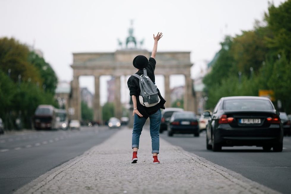 A woman waves from the middle of a road facing Berlin's Brandenburg Gate