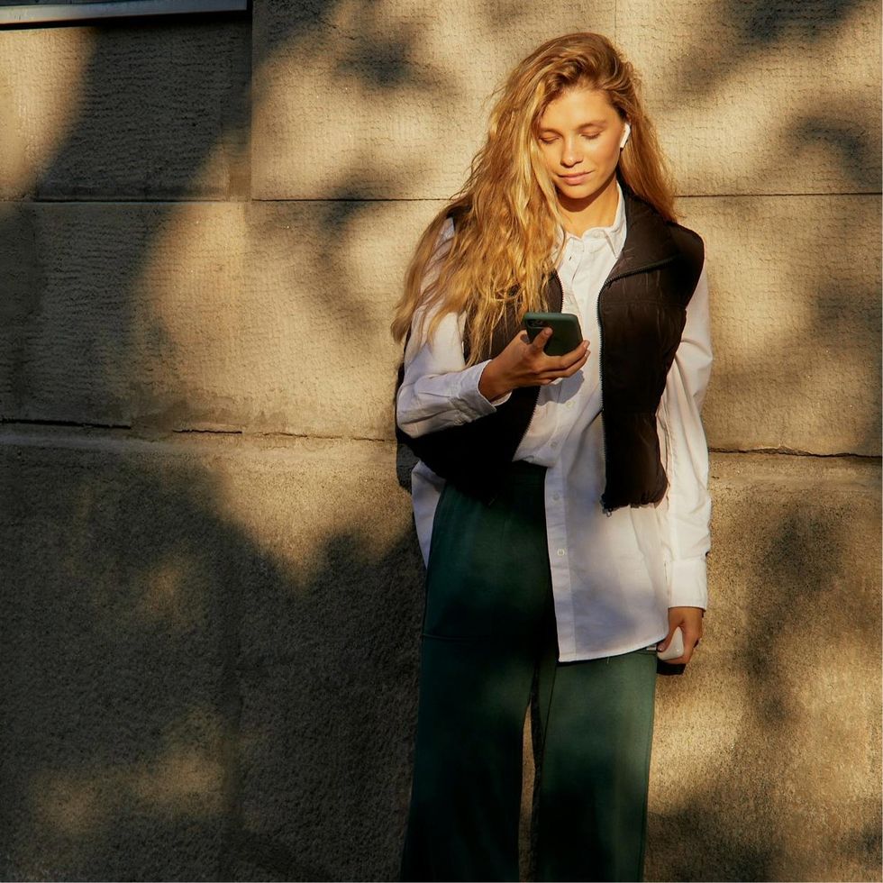 a woman wearing a cute vest looking at her phone