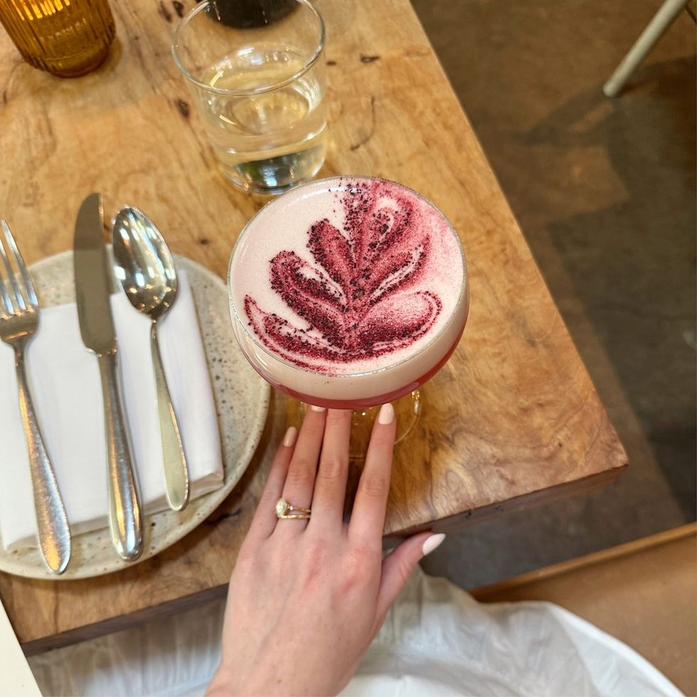 a woman with a beautiful fuchsia cocktail in front of her at dinner