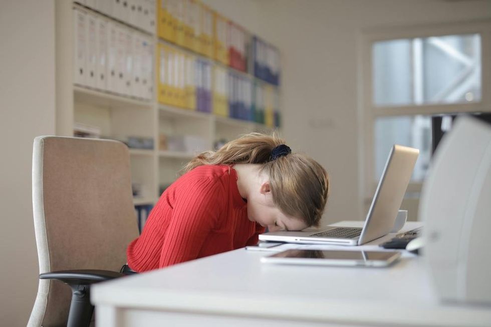 a woman with her head down on her desk