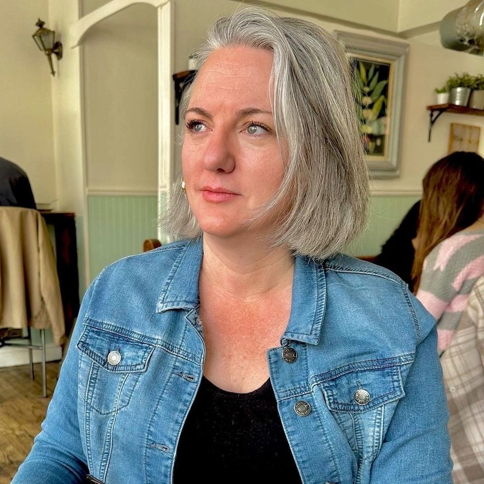 a woman with silver hair sitting in a coffee shop
