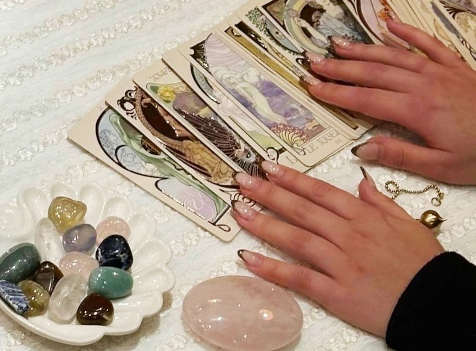 a woman working with crystals and a deck of tarot cards