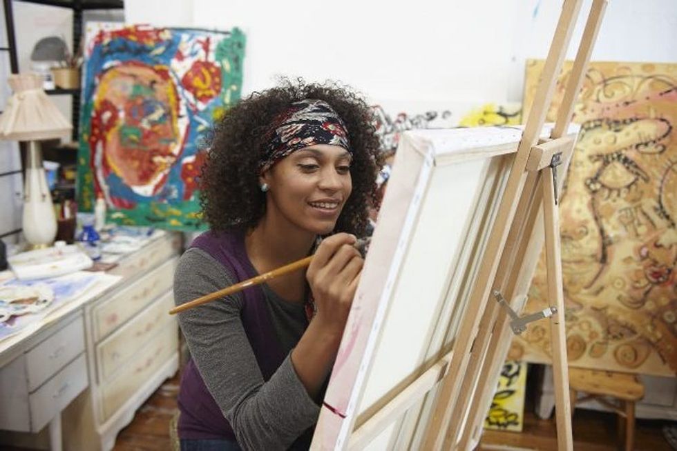 A woman works on a painting in her home studio