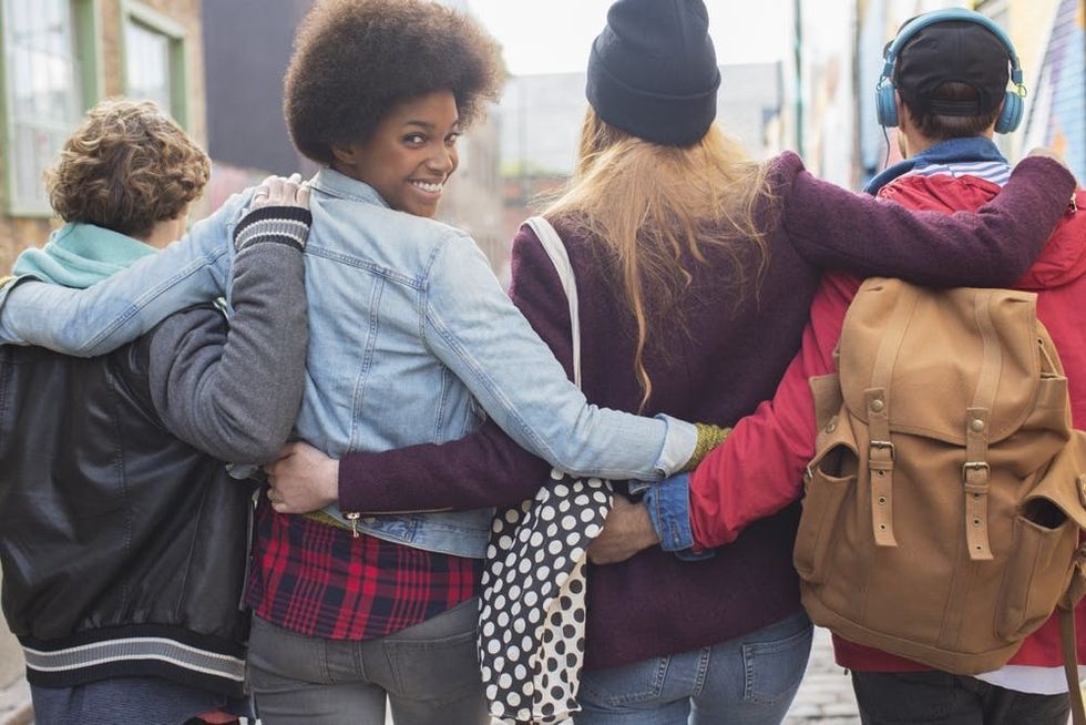 A young woman turns back to smile as she walks down the street with friends