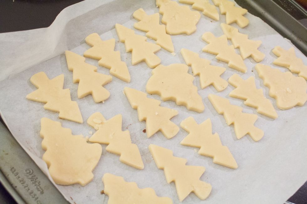 Add your shortbread cookie cutouts to the cookie tray lined with parchment paper. The next step we will be painting the trees!