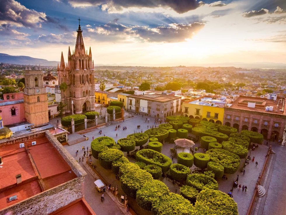 Aerial view of a Gothic church and plaza at sunset in San Miguel de Allende.