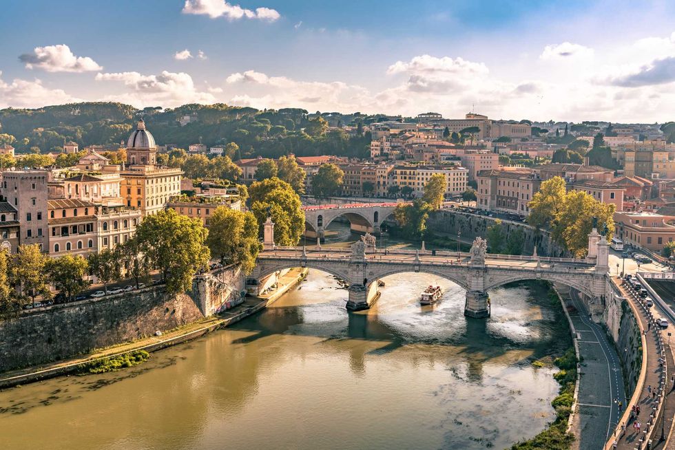 Aerial view of a historic bridge over a river in a sunlit cityscape.