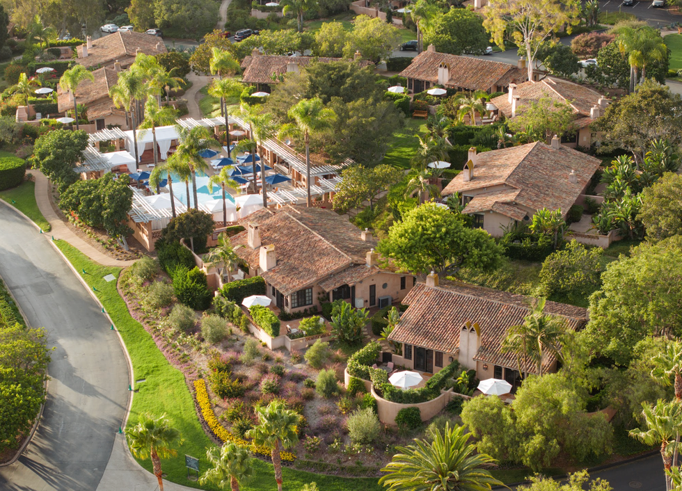 Aerial view of a resort with rustic villas, lush gardens, and a pool area.