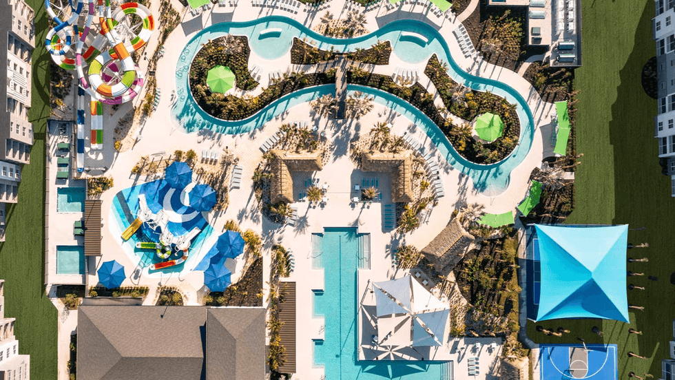 Aerial view of a water park with pools, slides, lazy river, and colorful umbrellas.