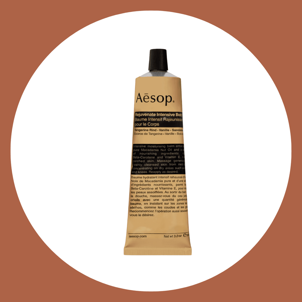 Aesop Rejuvenate Body Balm tube on a brown and white background.