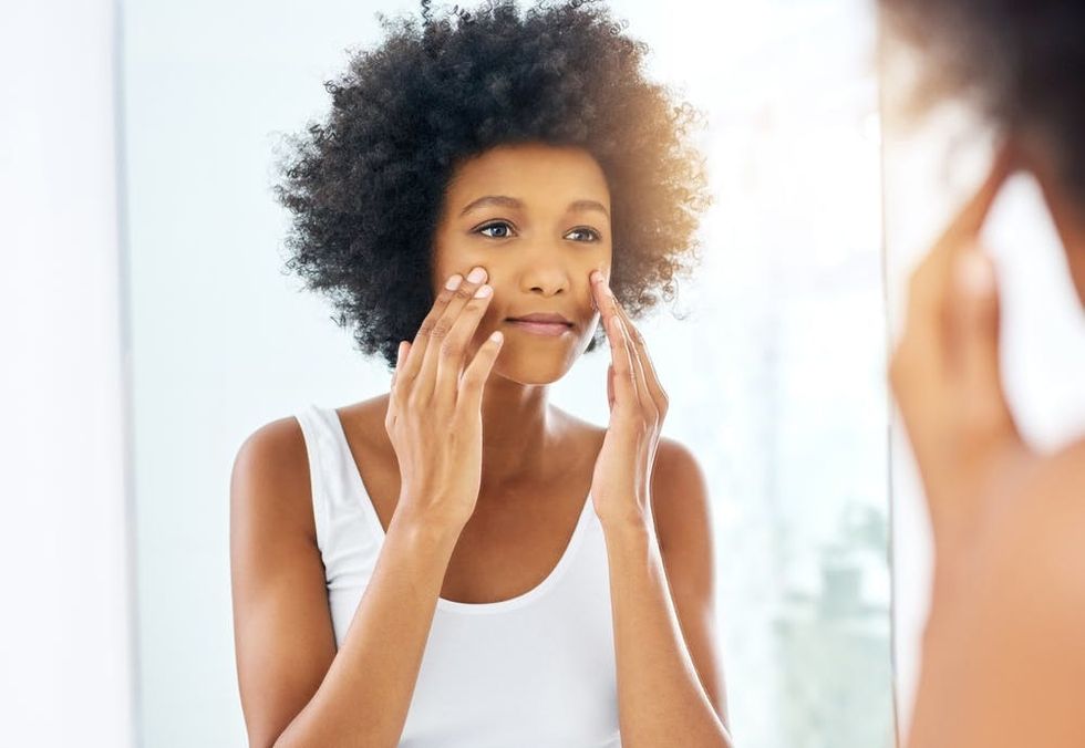 African American woman applying moisturizer.