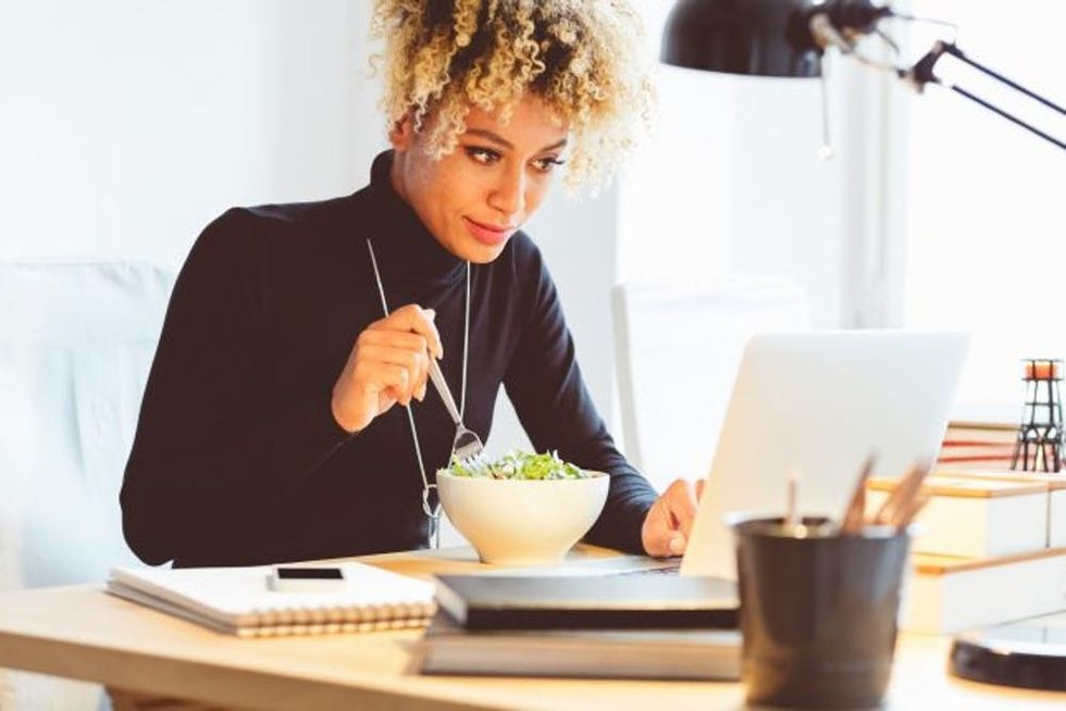 Afro american young woman eating lunch at the desk