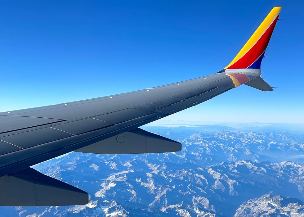 an airplane wing, flying over the mountains