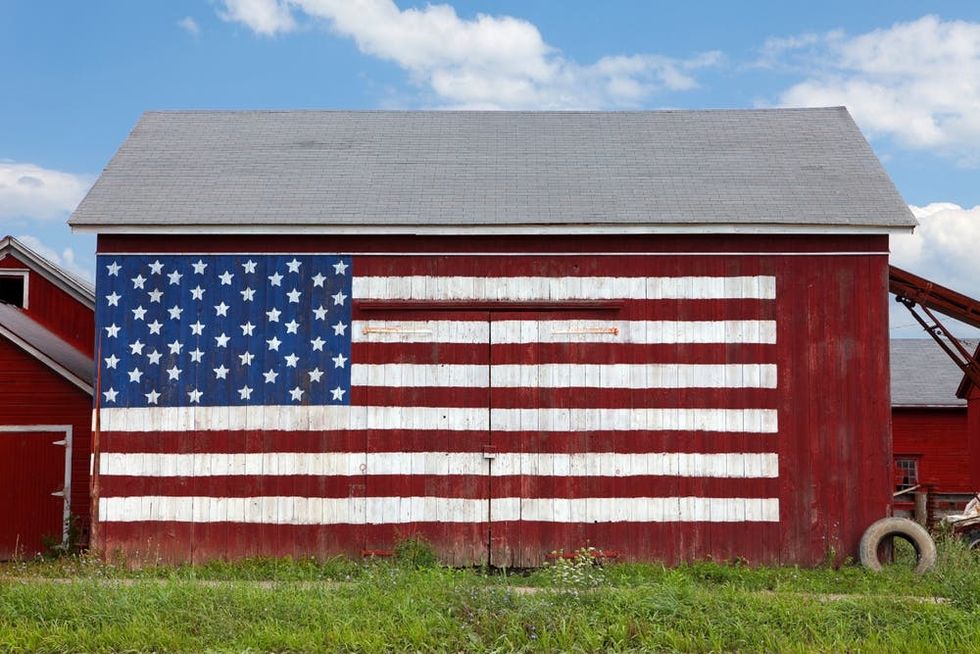 An American flag is painted on the side of a red wooden barn