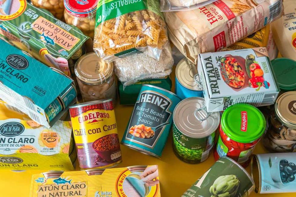 Assorted canned and packaged food items on a yellow surface.