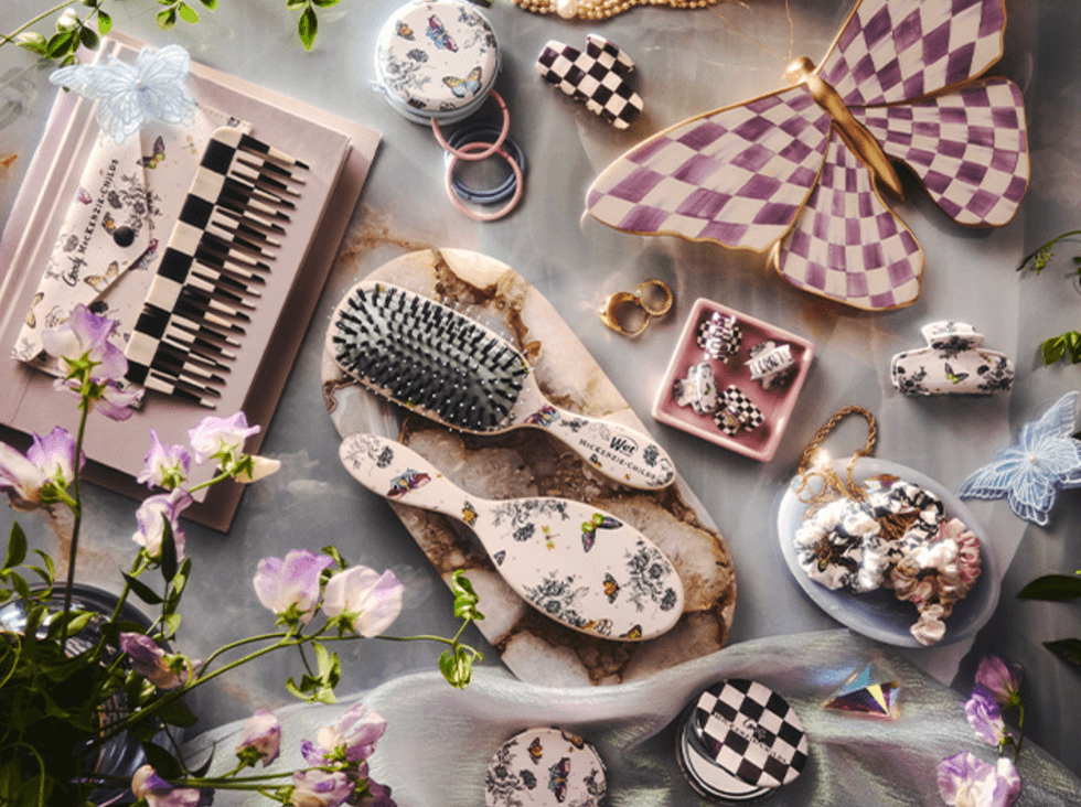 Assorted floral-themed vanity items on a table surrounded by flowers and butterfly decor.