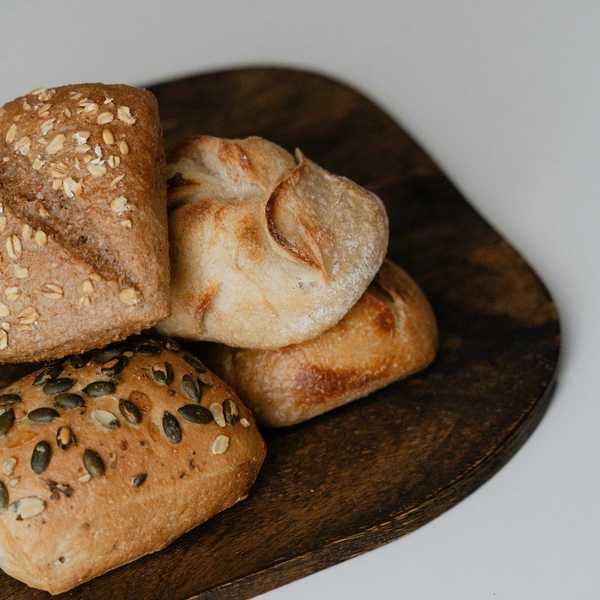 Assorted rustic bread rolls on a wooden serving board.