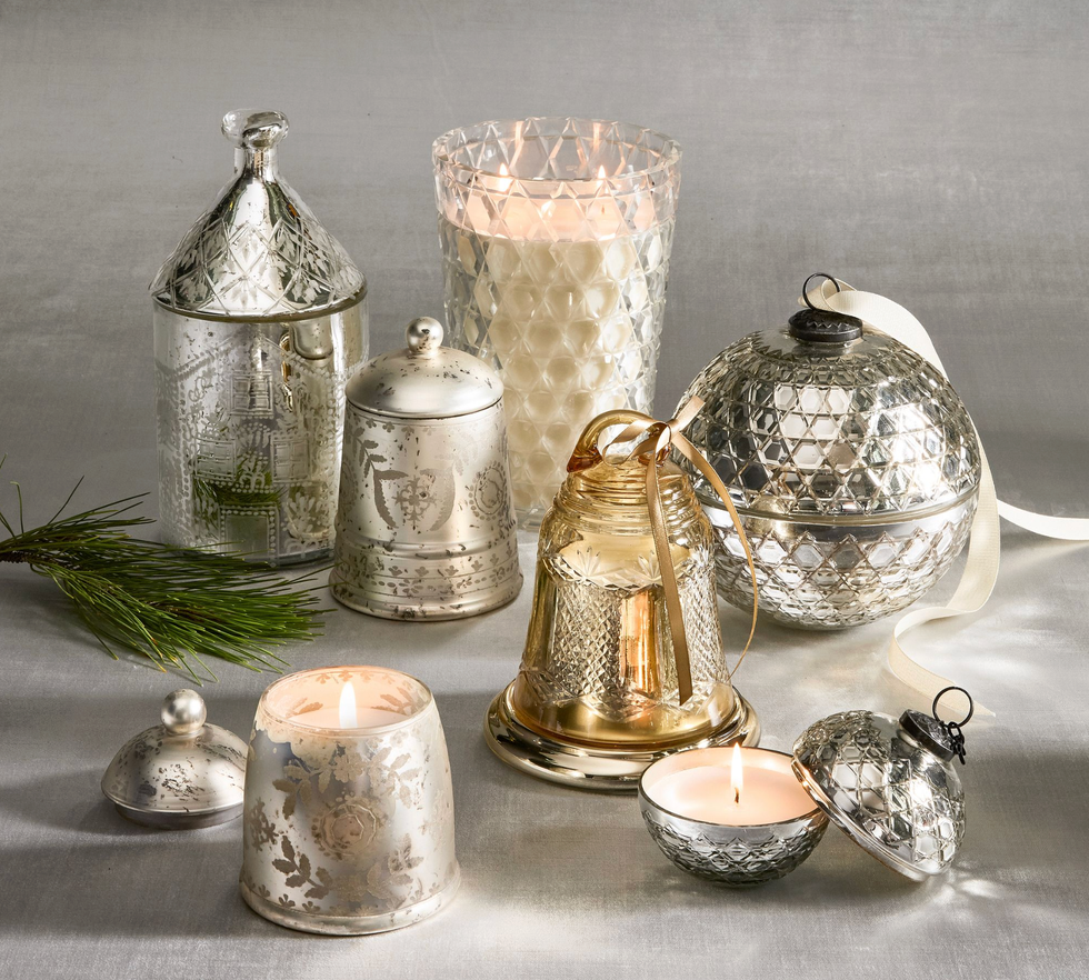Assorted silver and glass candle holders and ornaments on a gray background with pine sprig.