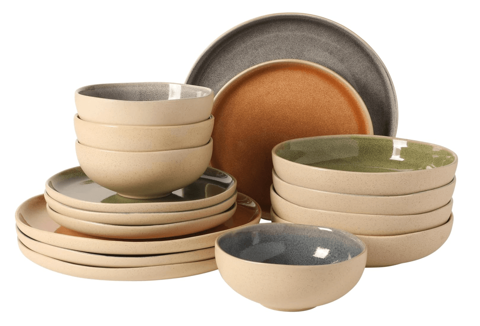 Assorted stoneware bowls and plates in neutral and earthy colors stacked together.