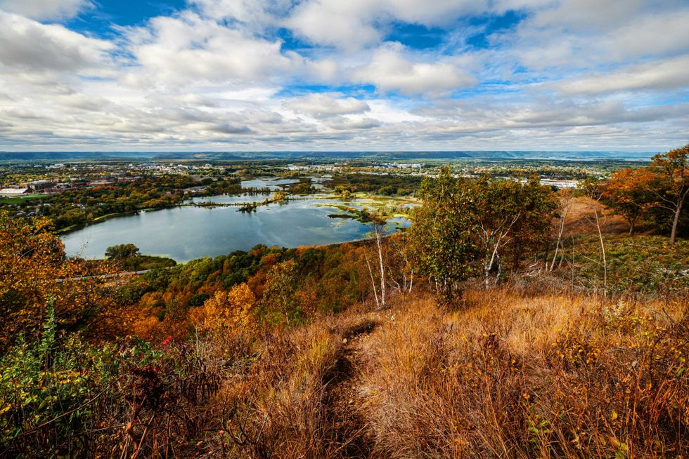 Autumn landscape with lake, colorful trees, and cloudy sky from a hilltop.