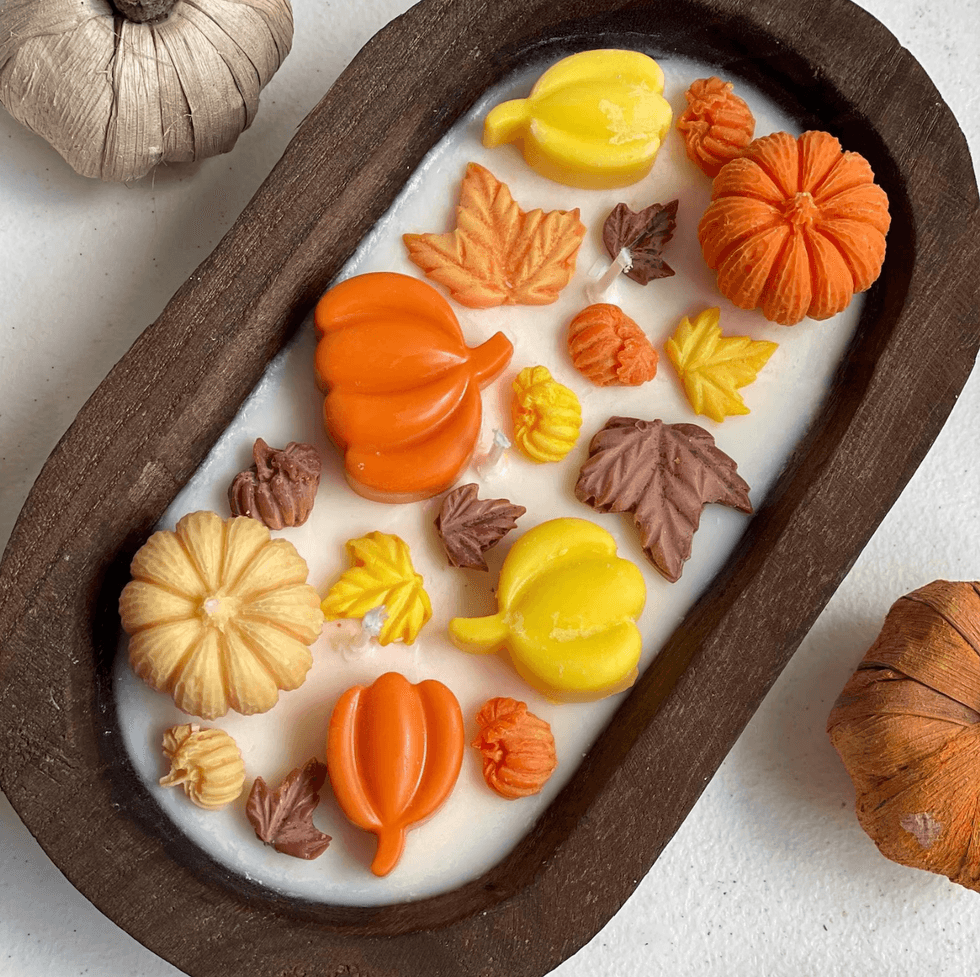 Autumn-themed wax melts shaped like pumpkins and leaves in a wooden bowl.