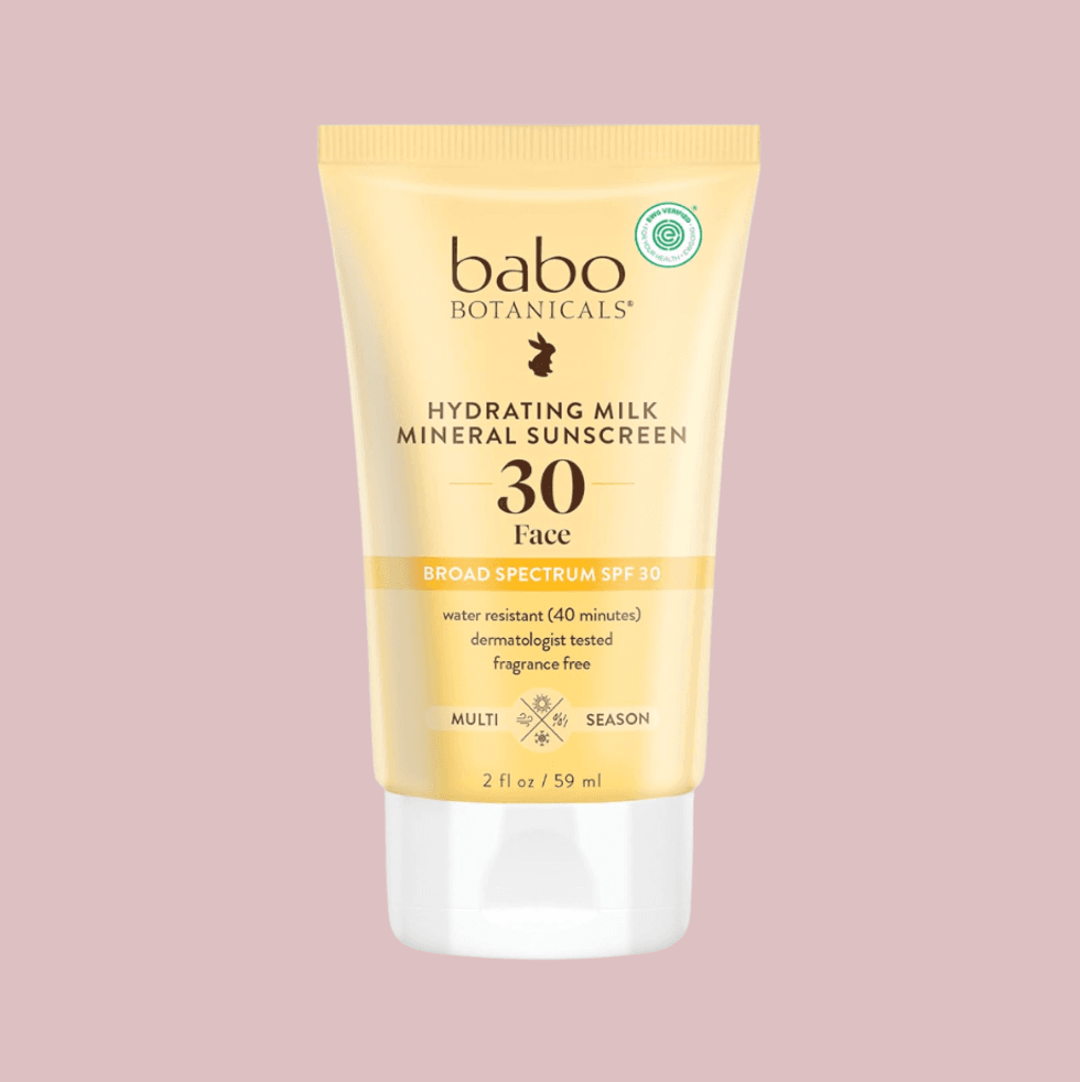 Babo Botanicals Hydrating Milk SPF 30 sunscreen tube on a pink background.