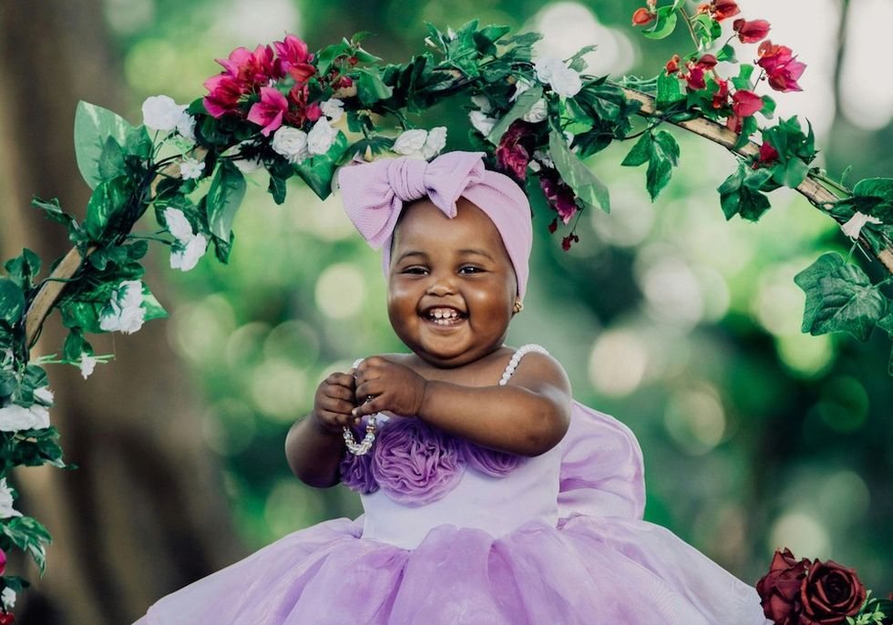 baby girl in a purple dress, surrounded by flowers