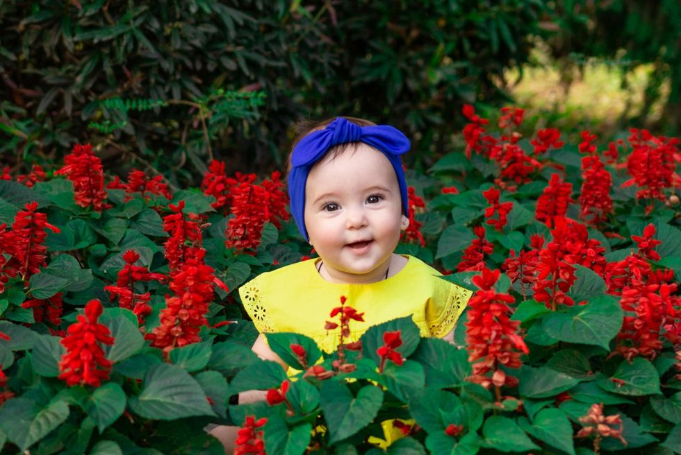 baby girl sitting in some red flowers