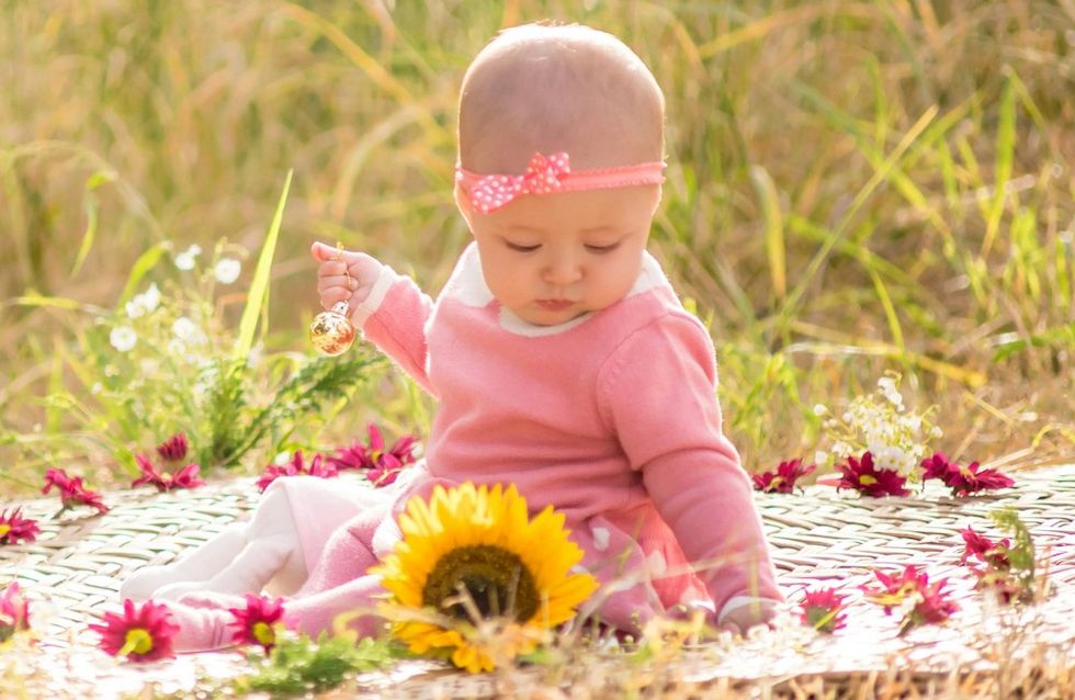 baby girl sitting on a blanket with flowers