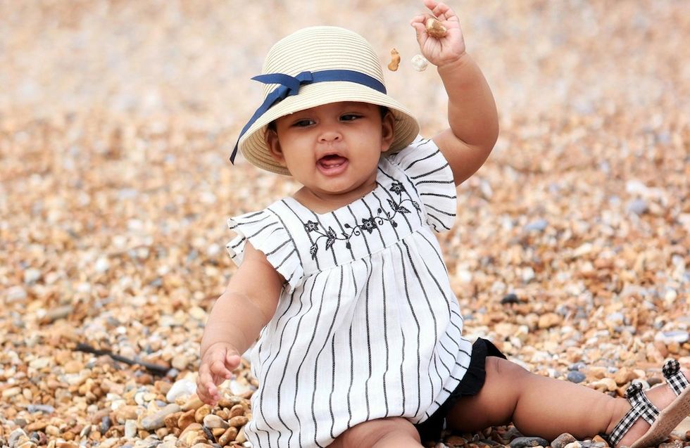 baby in a hat playing with rocks