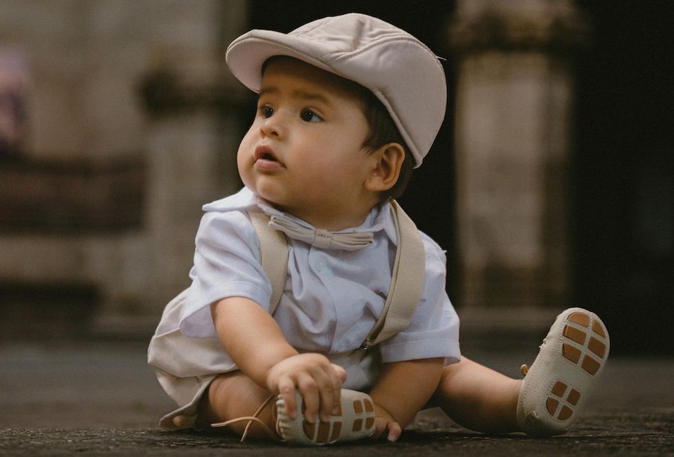 baby in suspenders, a bowtie, and a hat