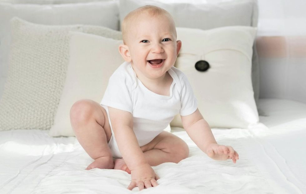 baby laughing on a bed
