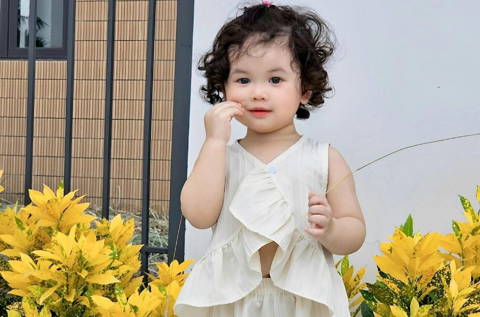 baby standing in front of yellow flowers
