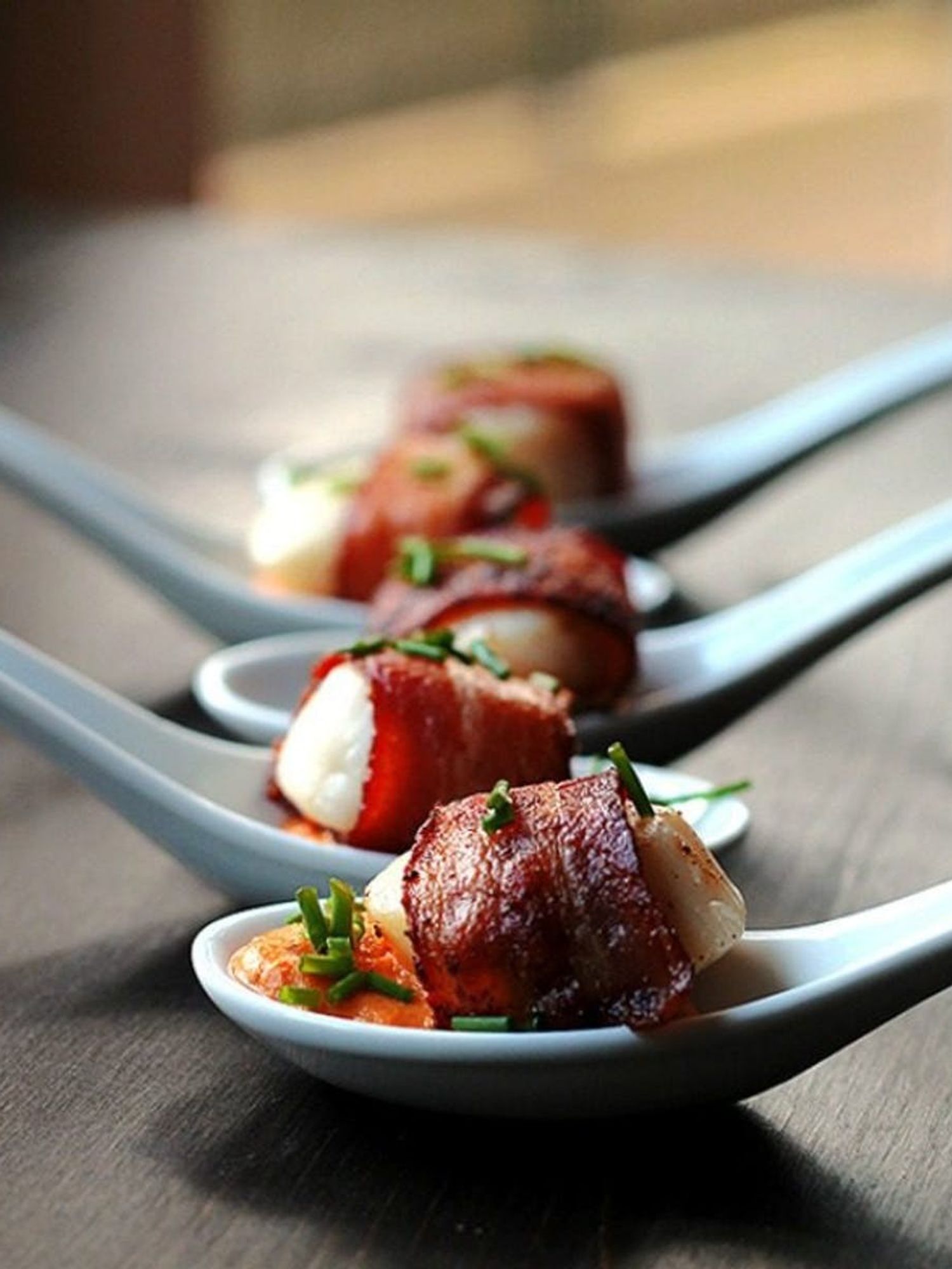 Bacon-Wrapped Scallops With Cajun Cream Sauce served in white china spoons