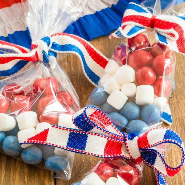 Bags of red, white, blue candies with ribbons on a wooden table.