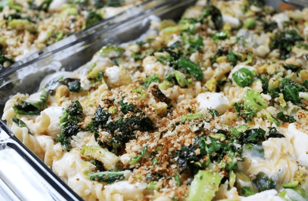 Baked pasta with spinach, breadcrumbs, and melted cheese in a glass dish.