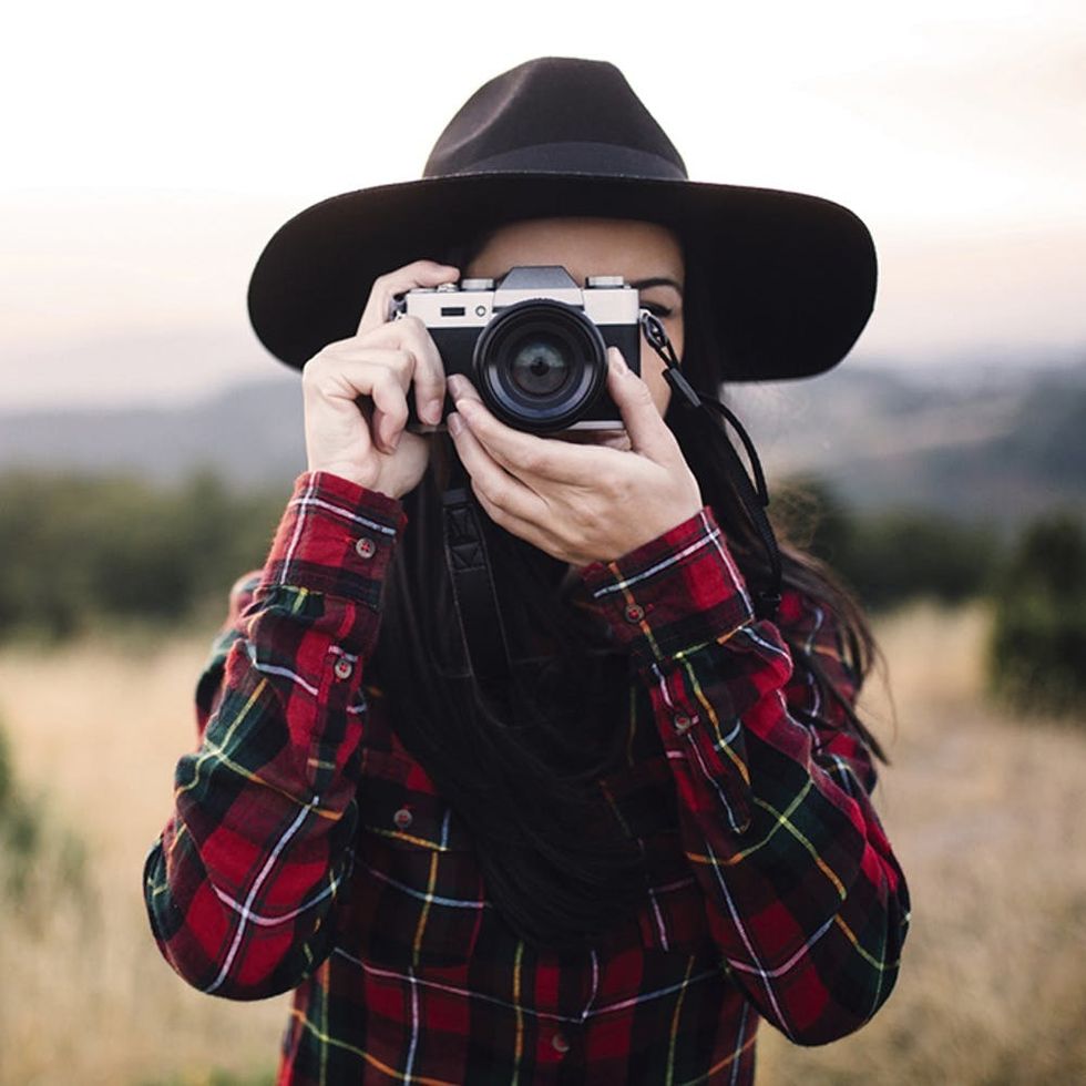 Beautiful female tourist holding retro camera and walking on the mountain