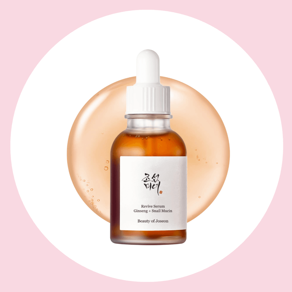 Beauty serum bottle with dropper on pink background.