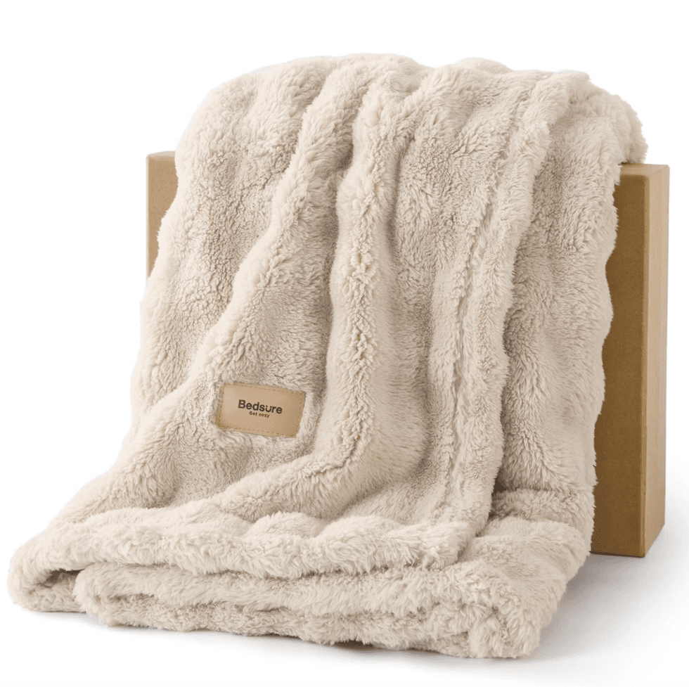 Beige fuzzy blanket draped over a cardboard box, with a "Bedsure" label.