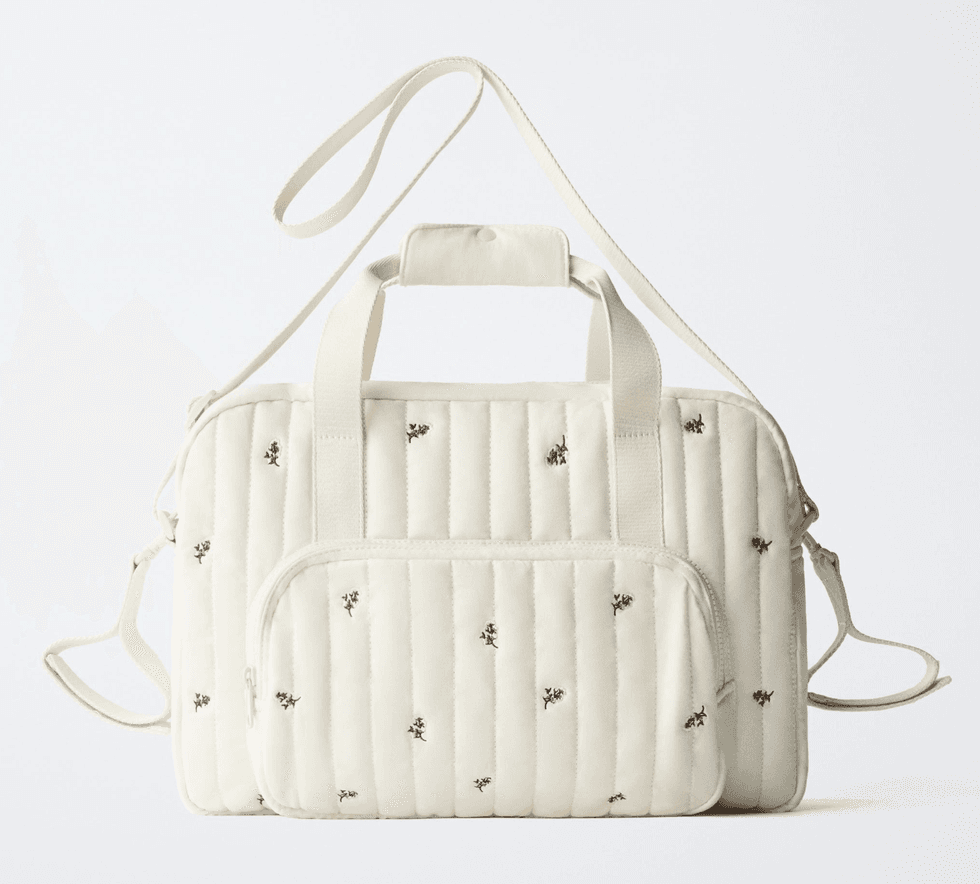 Beige quilted bag with floral pattern, multiple pockets, and adjustable straps.