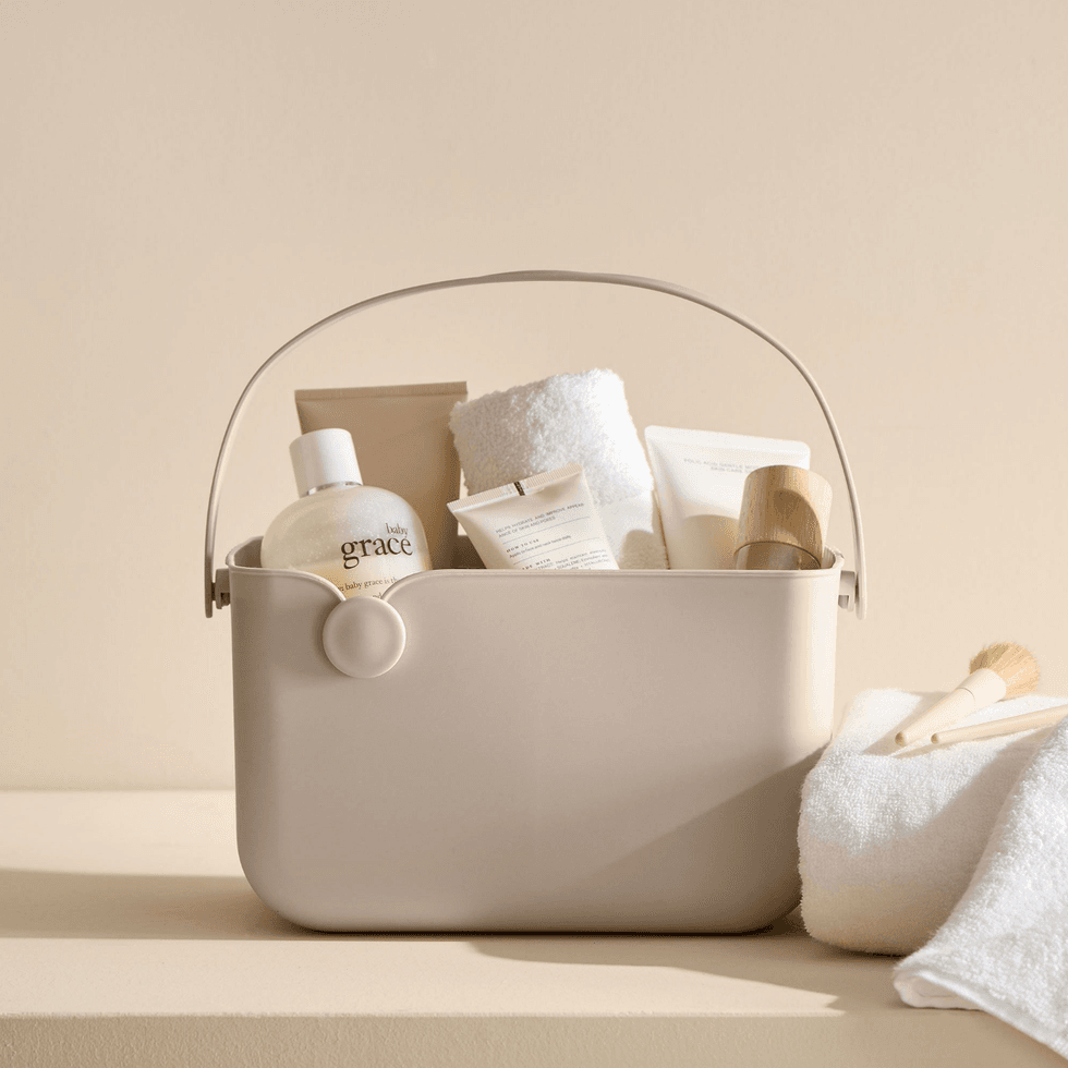 Beige tote with skincare products, towel, and brushes on a light surface.