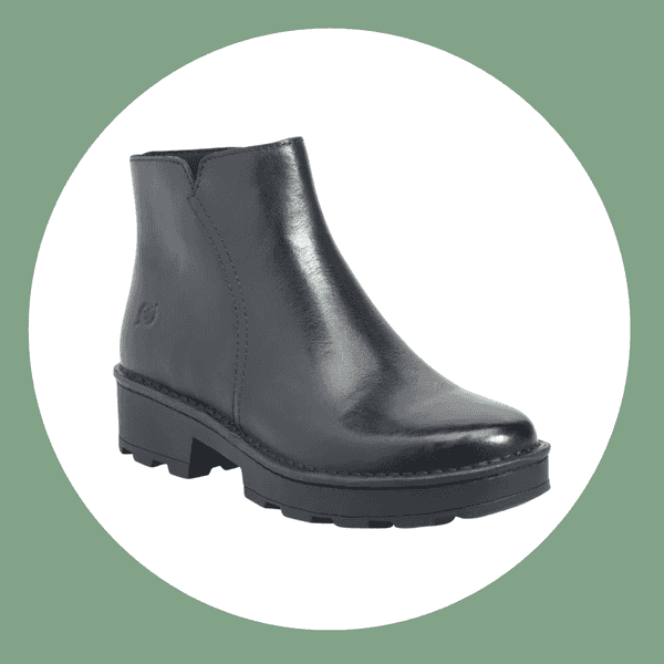 Black leather ankle boot with a side seam and chunky platform sole on a white circle.