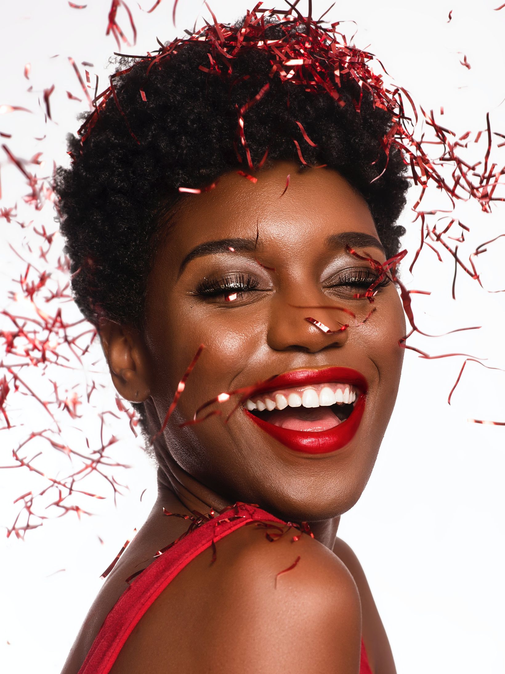 black woman wearing red lipstick, surrounded by red streamers