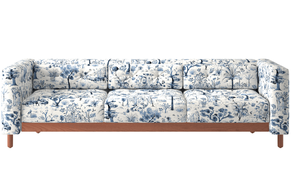 Blue and white patterned sofa with wooden legs and nature design.