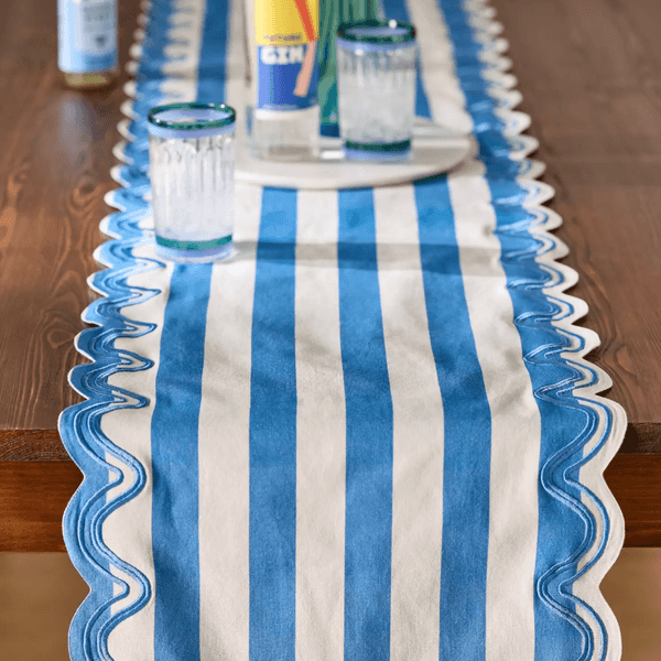 Blue and white striped table runner with wavy edges on a wooden table.